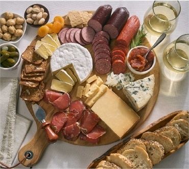 Charkbricka med ostar, skivade charkuterier, frukt och bröd